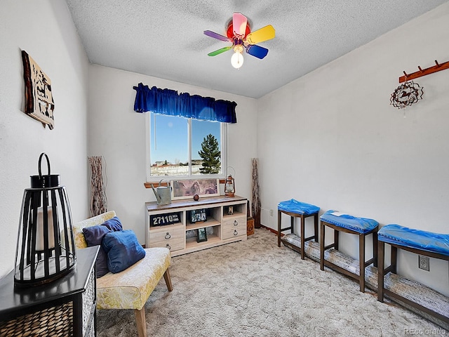 sitting room with carpet flooring, a textured ceiling, and ceiling fan