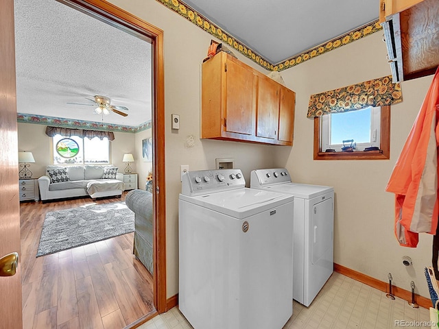 clothes washing area with cabinets, light wood-type flooring, a textured ceiling, ceiling fan, and independent washer and dryer