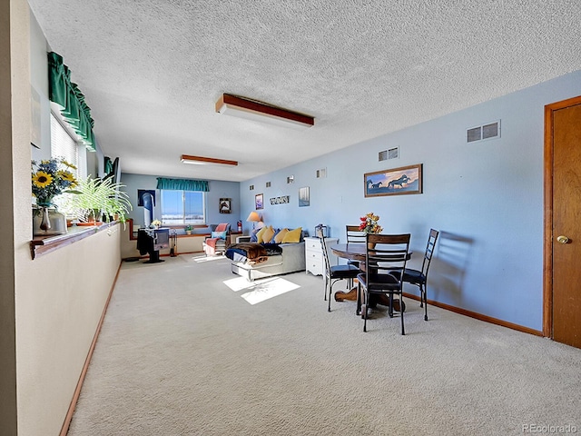 carpeted dining room featuring a textured ceiling