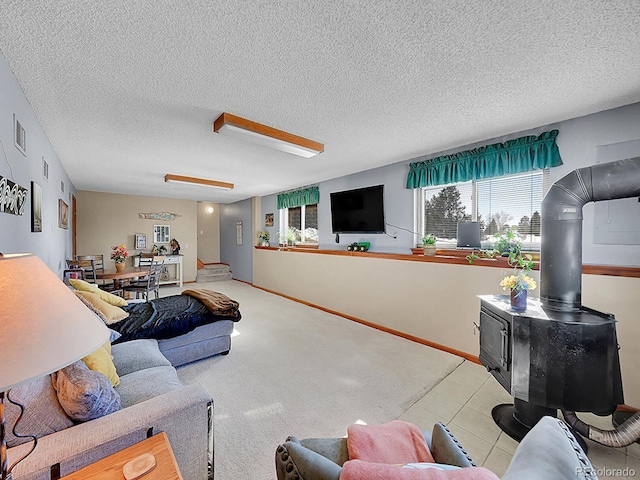 living room with a wood stove, light tile patterned floors, and a textured ceiling