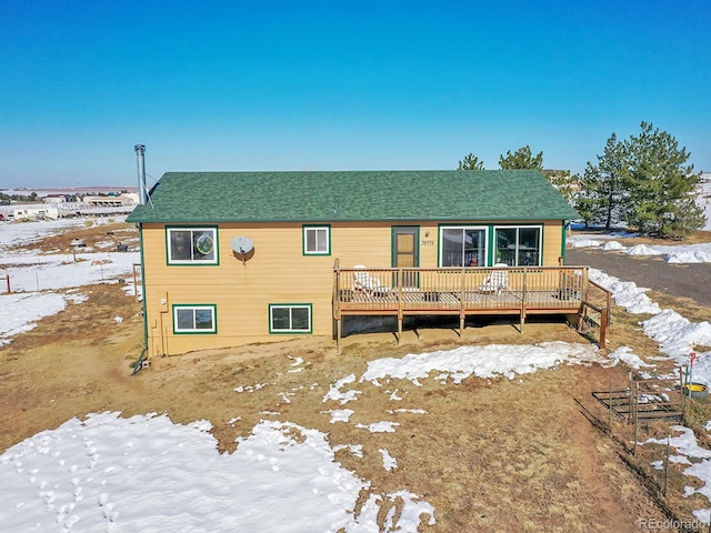 snow covered rear of property with a wooden deck