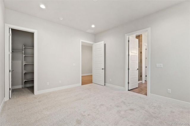 unfurnished bedroom with light carpet, a closet, and a walk in closet