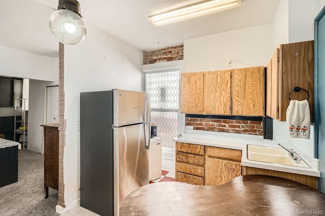 kitchen with freestanding refrigerator, light colored carpet, a sink, and light countertops