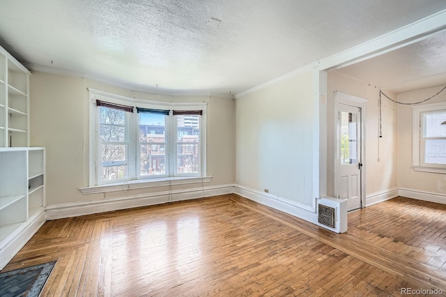 unfurnished living room featuring a textured ceiling, baseboards, visible vents, and hardwood / wood-style floors