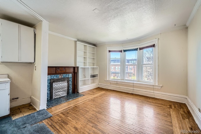 unfurnished living room featuring crown molding, a textured ceiling, baseboards, and a tile fireplace