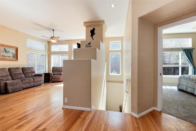 hallway with baseboards, an upstairs landing, a healthy amount of sunlight, and wood finished floors