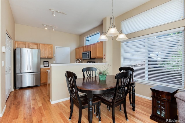 dining room featuring track lighting, baseboards, and light wood finished floors