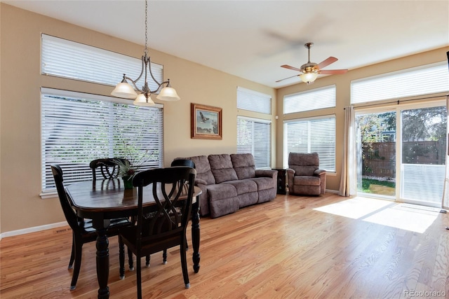 dining room featuring baseboards, light wood-style flooring, and ceiling fan with notable chandelier