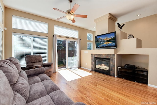 living room featuring a tiled fireplace, a ceiling fan, baseboards, recessed lighting, and light wood-type flooring