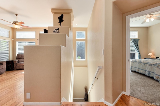 hallway featuring baseboards, an upstairs landing, plenty of natural light, and light wood-style floors