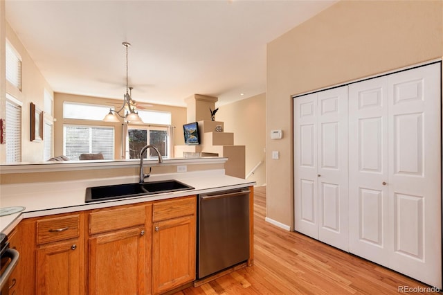 kitchen featuring hanging light fixtures, a sink, light wood-style floors, light countertops, and dishwasher
