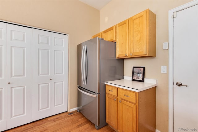 kitchen featuring light wood-type flooring, freestanding refrigerator, baseboards, and light countertops
