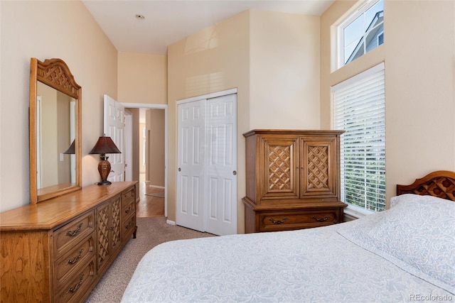 bedroom with a high ceiling, light colored carpet, and a closet