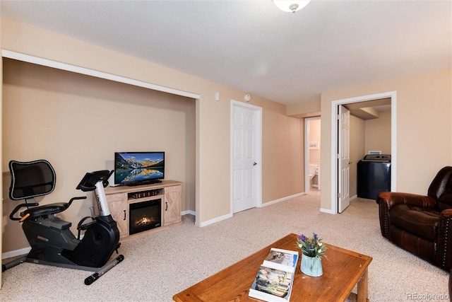 carpeted living room featuring baseboards, a glass covered fireplace, and washer / clothes dryer