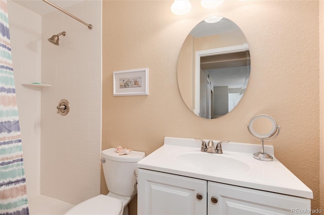 bathroom featuring vanity, toilet, and tiled shower