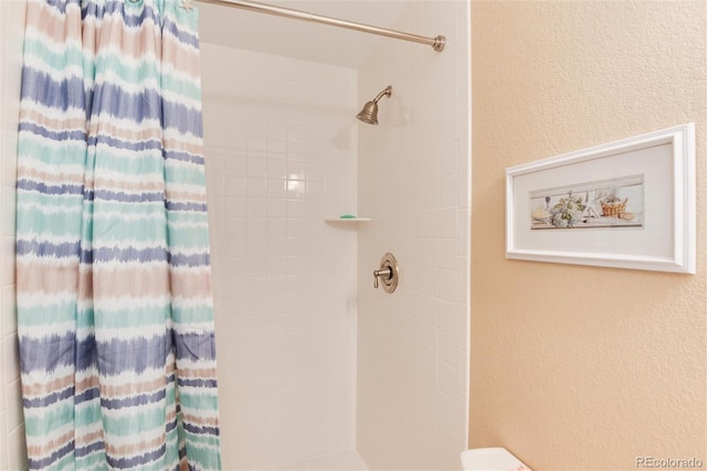 full bathroom featuring a textured wall and a tile shower