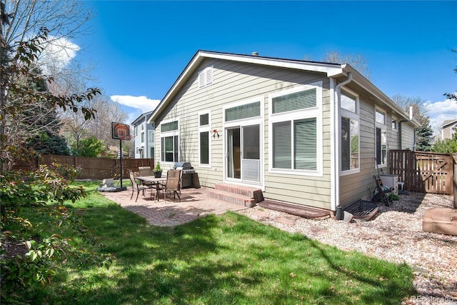 back of property with entry steps, a yard, a fenced backyard, and a patio area