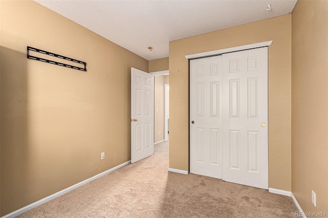 unfurnished bedroom with light carpet, a textured ceiling, and a closet