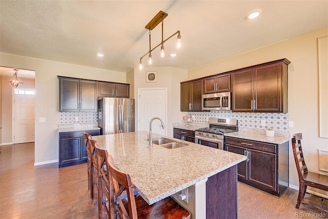 kitchen with sink, decorative light fixtures, decorative backsplash, a center island with sink, and appliances with stainless steel finishes