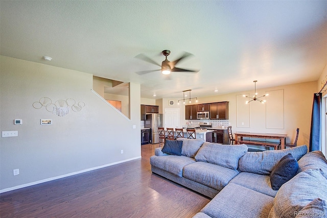 living room featuring ceiling fan with notable chandelier and dark hardwood / wood-style flooring