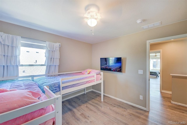 bedroom featuring multiple windows, hardwood / wood-style floors, and ceiling fan