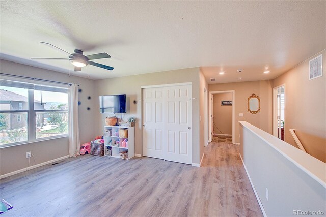 recreation room with light hardwood / wood-style floors, ceiling fan, and a textured ceiling