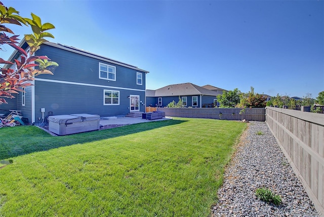 back of house with a patio area, a lawn, and a hot tub