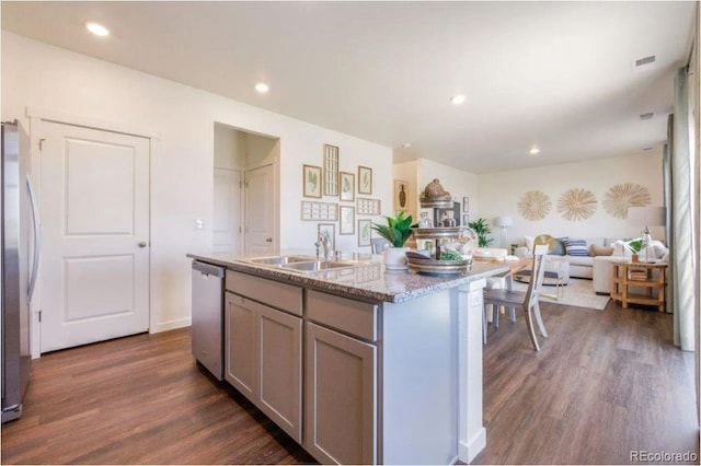 kitchen featuring dark wood-type flooring, stainless steel appliances, a center island with sink, and sink