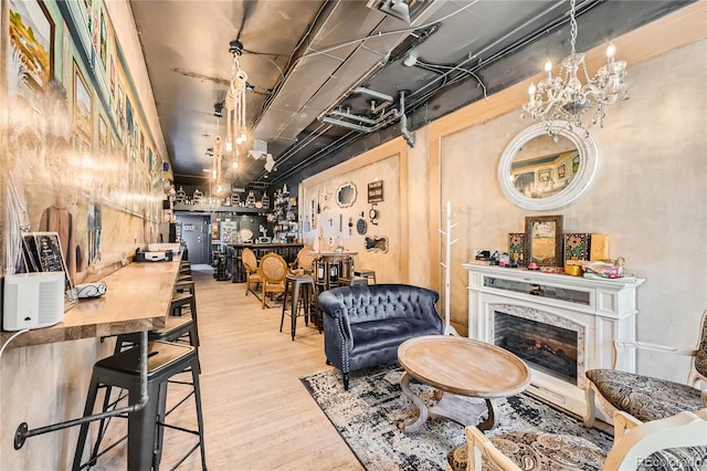 living room with bar area, an inviting chandelier, light wood-type flooring, and a premium fireplace