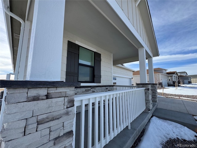 view of snowy exterior featuring a garage and a porch