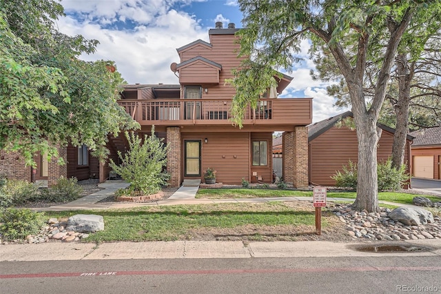 view of front of home featuring a balcony, a front yard, and a garage