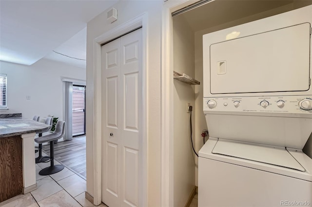 laundry room with stacked washer / dryer and light tile patterned floors