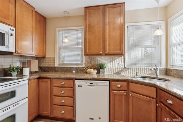 kitchen with sink, light stone counters, pendant lighting, white appliances, and decorative backsplash