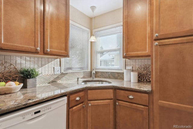 kitchen featuring sink, hanging light fixtures, dark stone countertops, white dishwasher, and backsplash