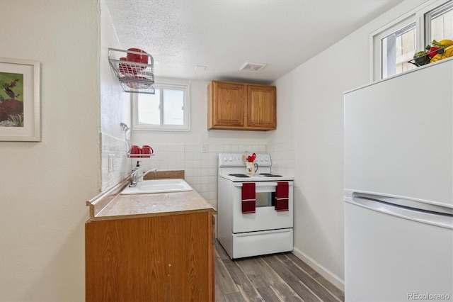 kitchen with white appliances, dark hardwood / wood-style floors, sink, and a textured ceiling