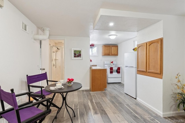 kitchen featuring sink, white appliances, decorative backsplash, and light wood-type flooring