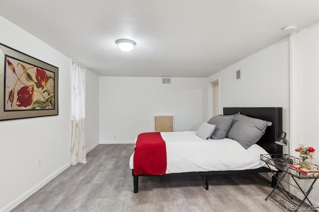 bedroom featuring light hardwood / wood-style flooring and a textured ceiling