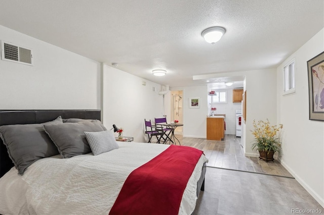 bedroom featuring a textured ceiling, multiple windows, and light wood-type flooring