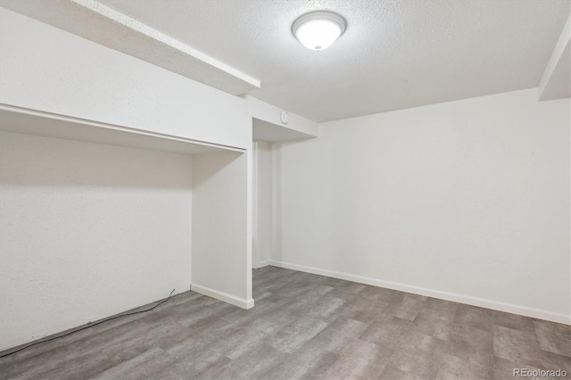 basement featuring light hardwood / wood-style floors and a textured ceiling