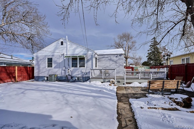 snow covered property featuring a wooden deck and central AC unit