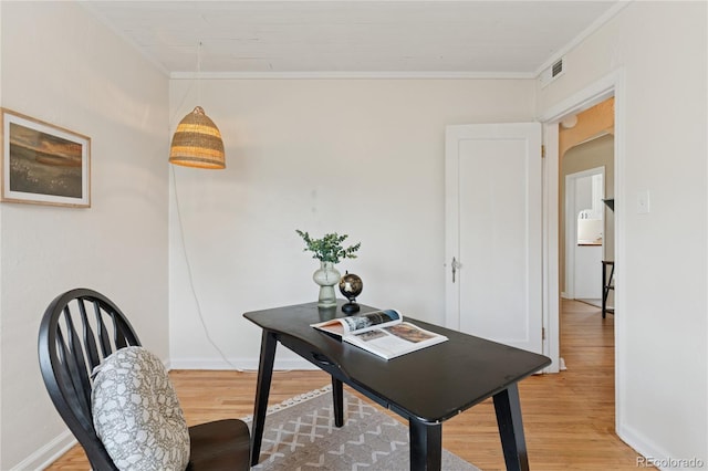 office with baseboards, visible vents, ornamental molding, and light wood-style floors