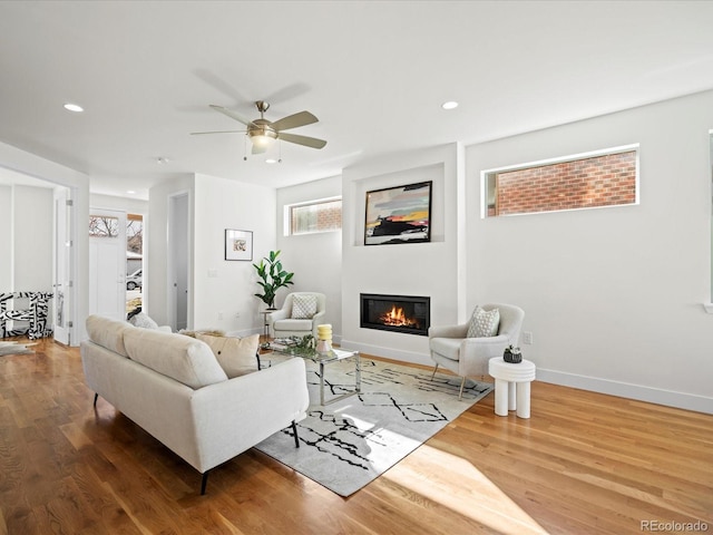 living area with recessed lighting, baseboards, wood finished floors, and a glass covered fireplace