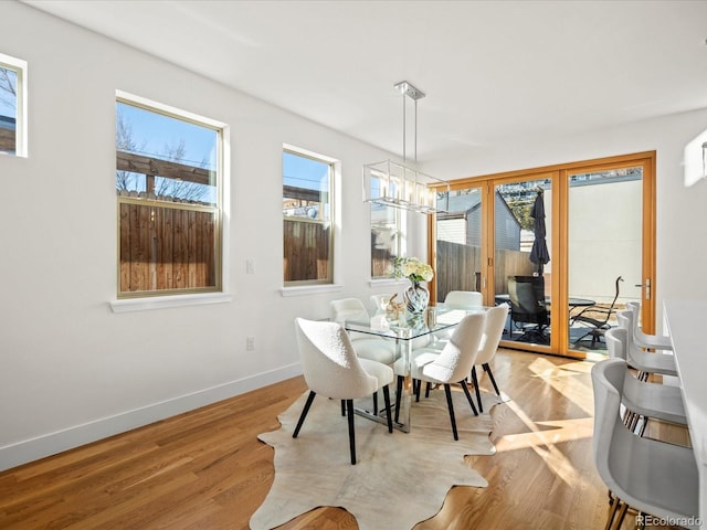 dining room featuring a notable chandelier, light wood finished floors, and baseboards