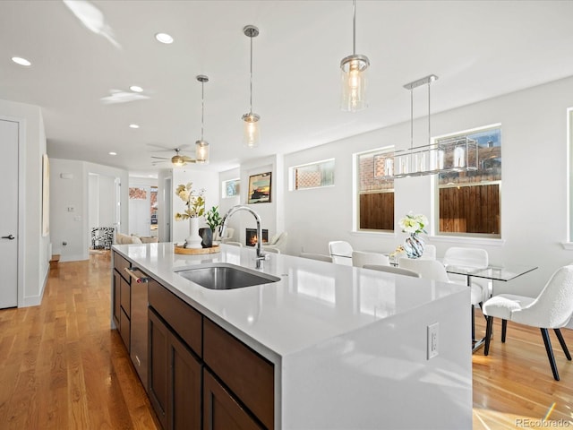 kitchen with light countertops, decorative light fixtures, a sink, and light wood-style flooring