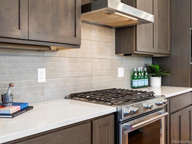 kitchen featuring light countertops, decorative backsplash, stainless steel gas stove, dark brown cabinets, and ventilation hood