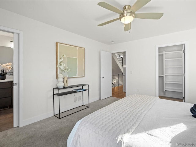 bedroom featuring carpet floors, a ceiling fan, baseboards, a closet, and a walk in closet