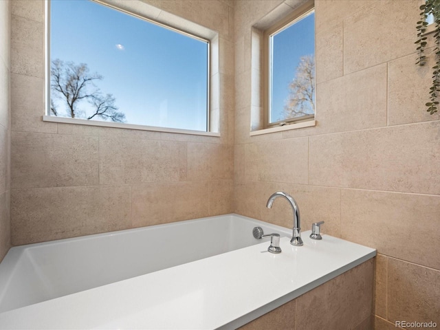 full bath featuring a garden tub and tile walls