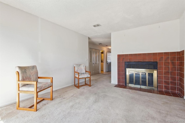 unfurnished room featuring light carpet, a tile fireplace, and a textured ceiling