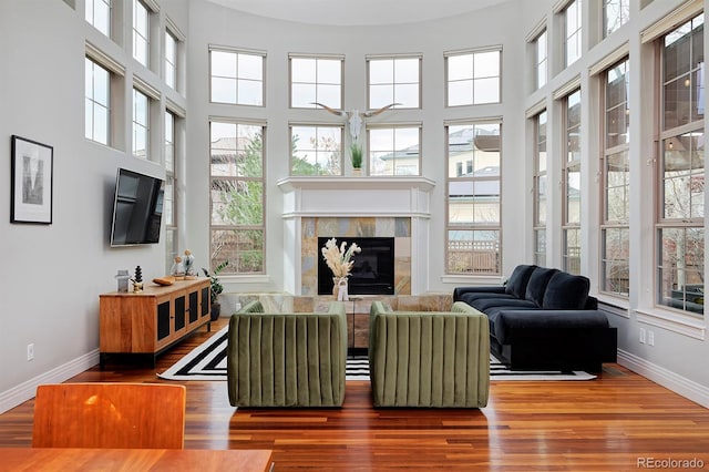 8044 E 24th Ave, Denver, CO 80238 - living room featuring baseboards, wood finished floors, a glass covered fireplace, and a towering ceiling