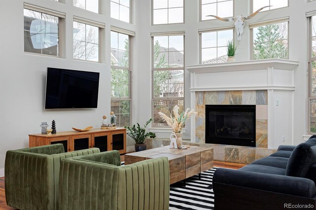 8044 E 24th Ave, Denver, CO 80238 - living area featuring a fireplace, a towering ceiling, and wood finished floors